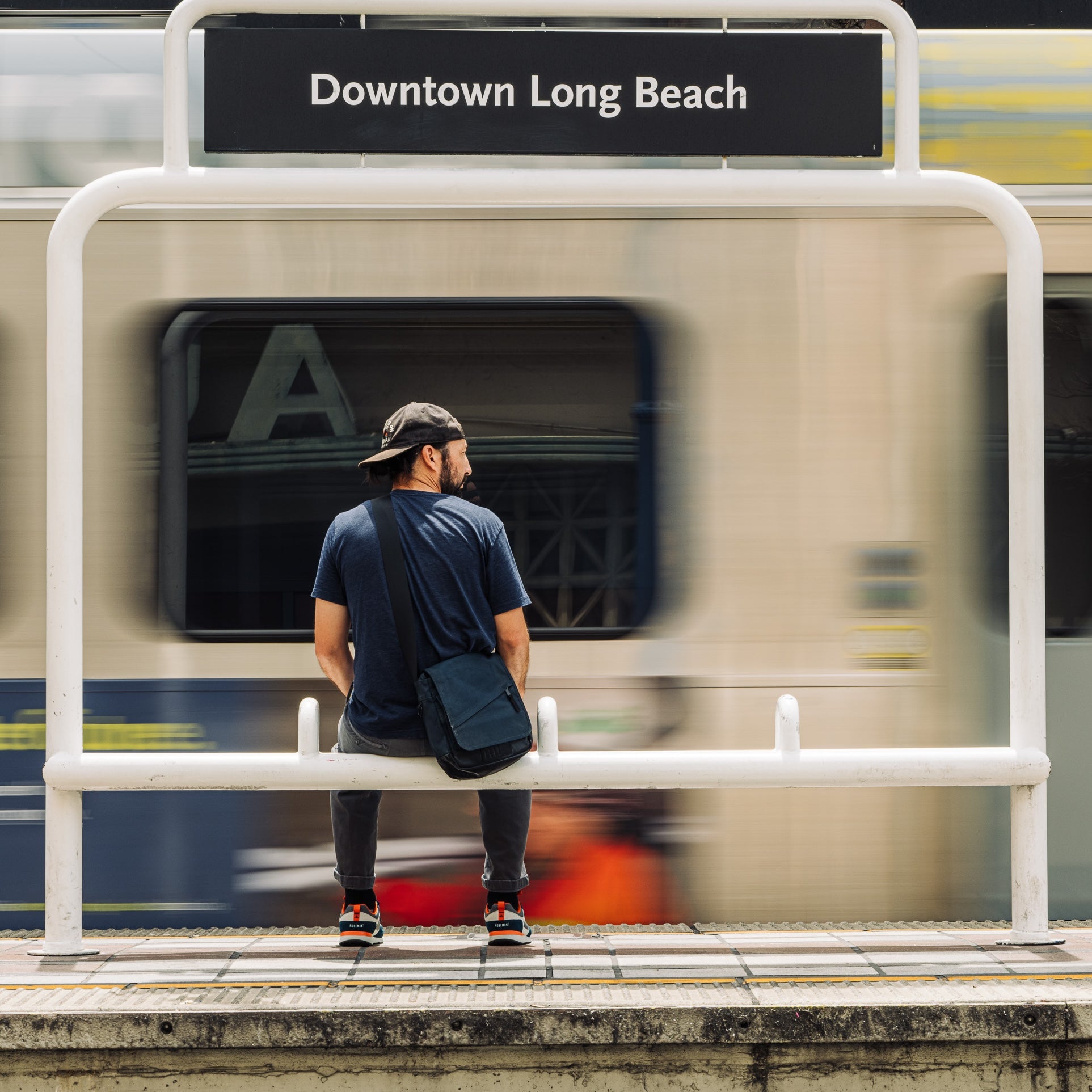 A person wearing Ridgemont Escape sneakers in Navy Charcoal sitting on a bench at the Downtown Long Beach train station.