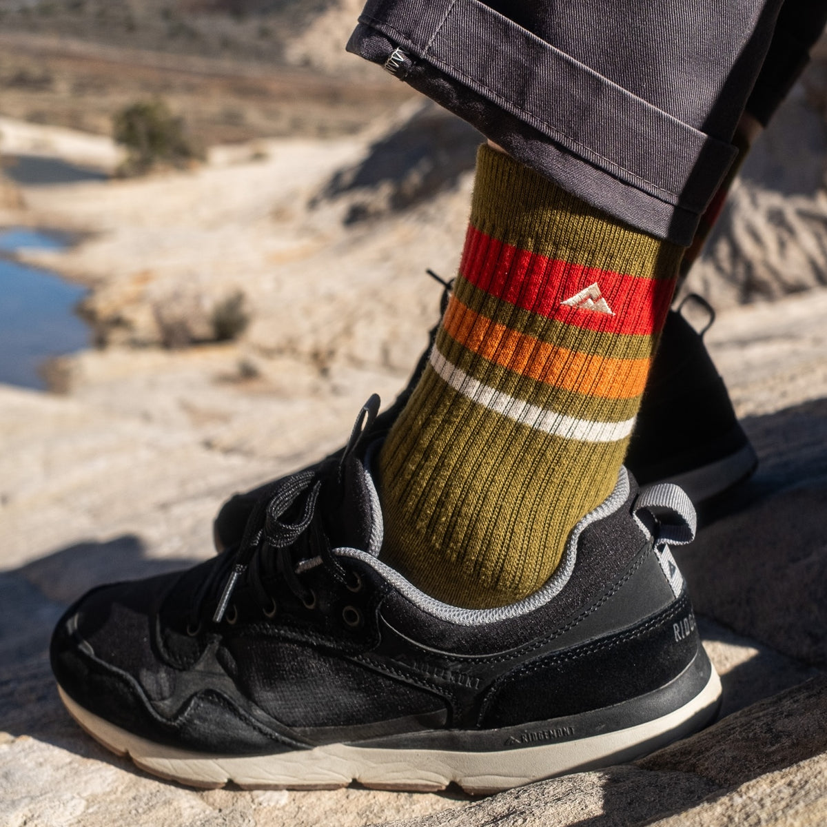 Ridgemont shoe sneaker Escape in color black with crew trailblazer olive green sock in St. George, Utah. Escape has black ripstop poly, white CMEVA midsole, real rubber tread in color gum, grey/gray inner lining, DWR coating, black laces, black oiled suede. Comfort, easy break in, everyday walking, everyday comfort, shoe, sneaker, all season.