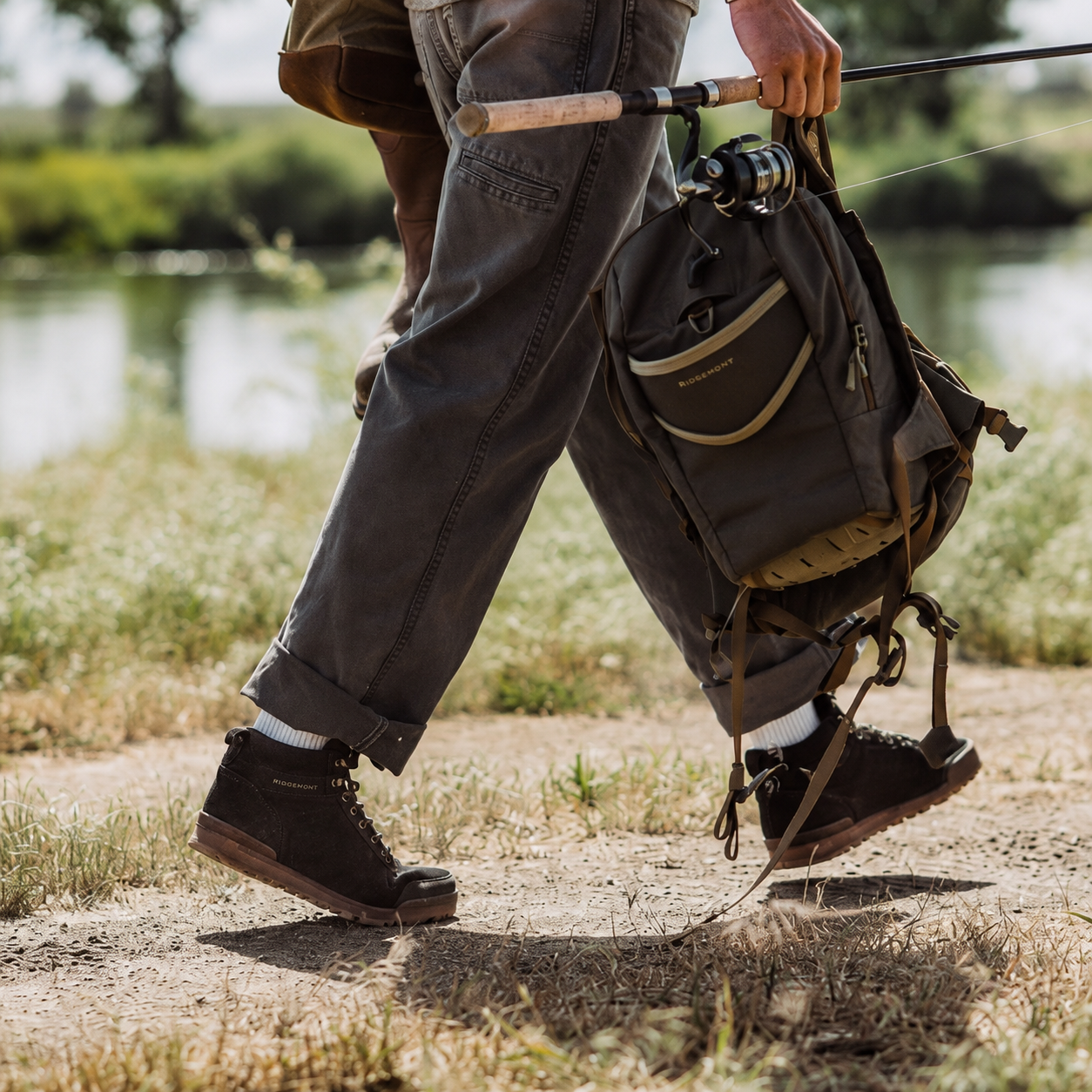 Fisherman wears Ridgemont Monty boot in Black Gum with Fishing pole and backpack in hand 